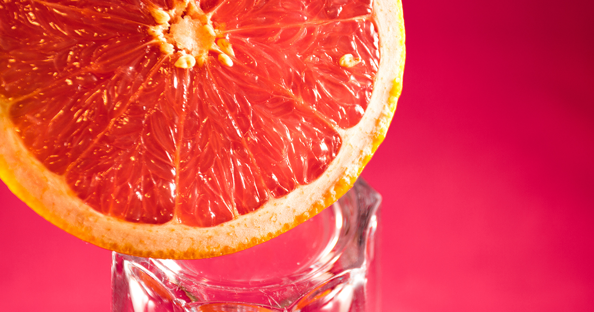 En halv grapefrukt som balanserar på kanten av ett glas